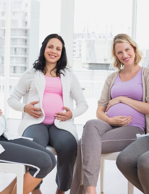 Smiling pregnant women sitting together at antenatal class at the hospital